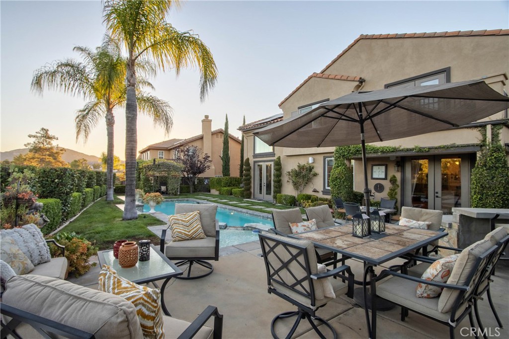 32815 Cleveland Street Temecula, CA 92592 - Photo 49 of 71 a view of a patio with couches table and chairs under an umbrella with a garden