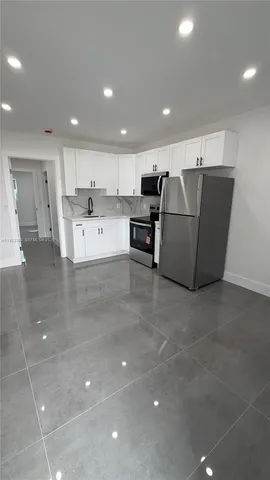 a large white kitchen with a large window and stainless steel appliances