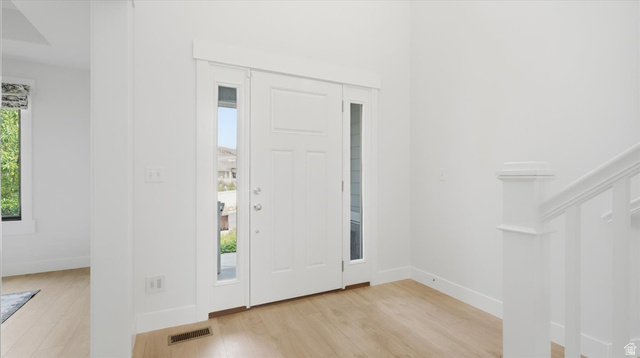2038 East Ranch Road Eagle Mountain, UT 84005 - Photo 7 of 66 Entryway featuring a paneled door with glass side lites, light wood-finish flooring, white baseboards, and a white staircase railing