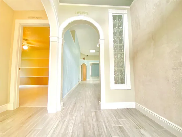 a view of a hallway with wooden floor and a bathroom