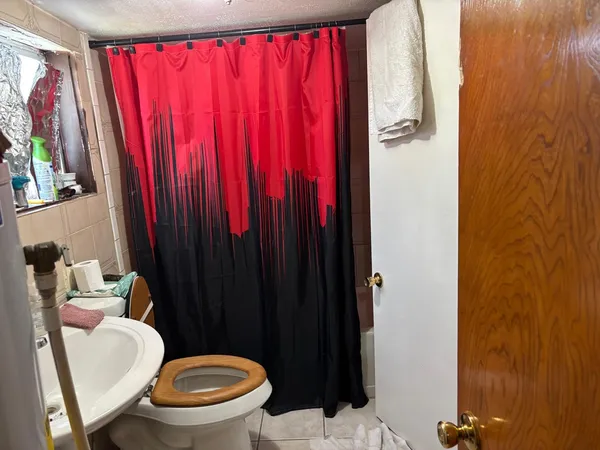 a bathroom with a toilet a sink and curtain