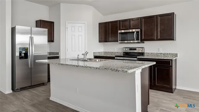 a kitchen with stainless steel appliances granite countertop a refrigerator stove and microwave