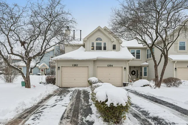 a front view of a house with a yard covered in snow