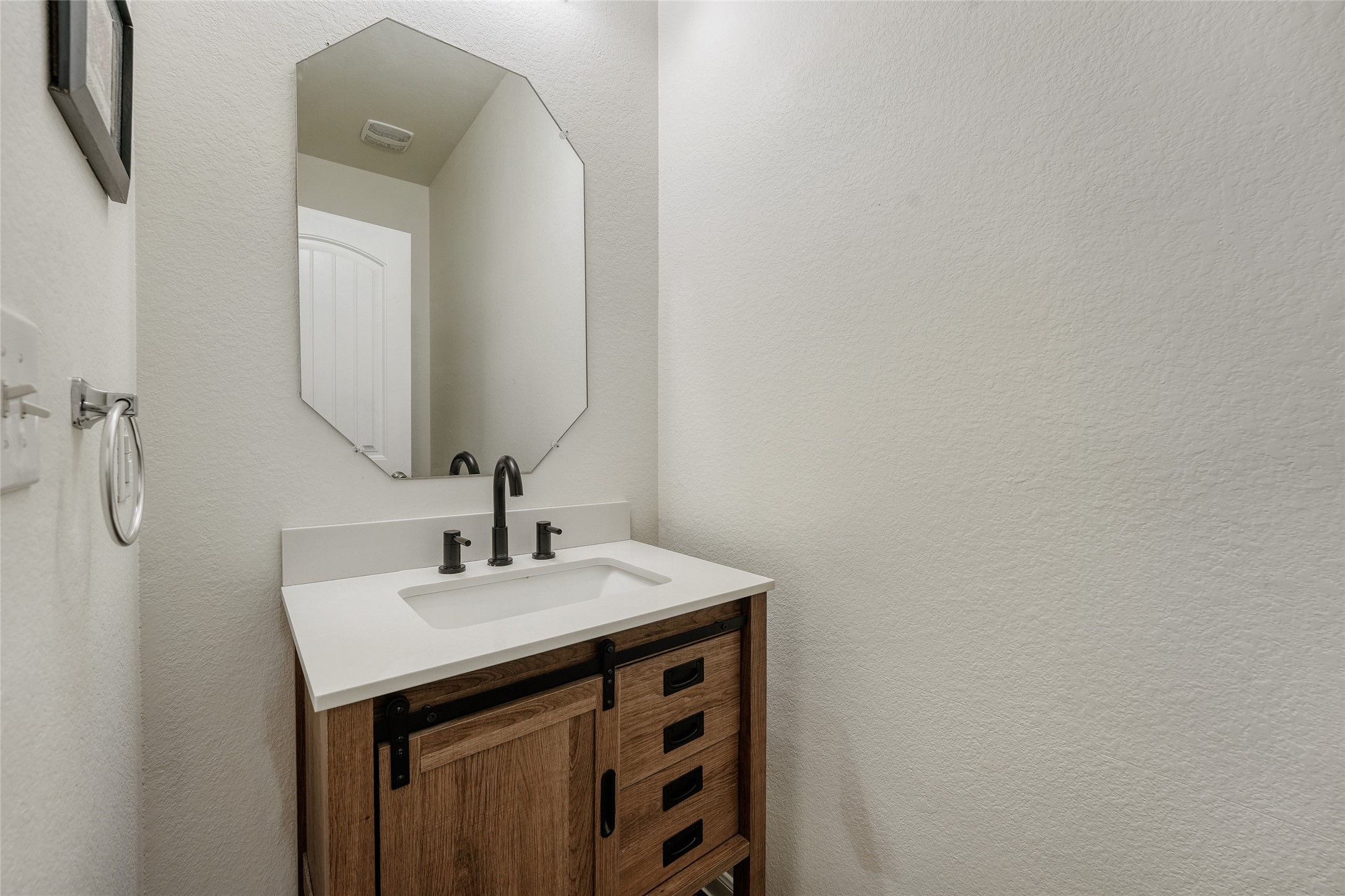 15105 Shell Bark Cove Austin, TX 78724 - Photo 17 of 30 A well-appointed powder room features a distinctive barn door vanity and modern fixtures.