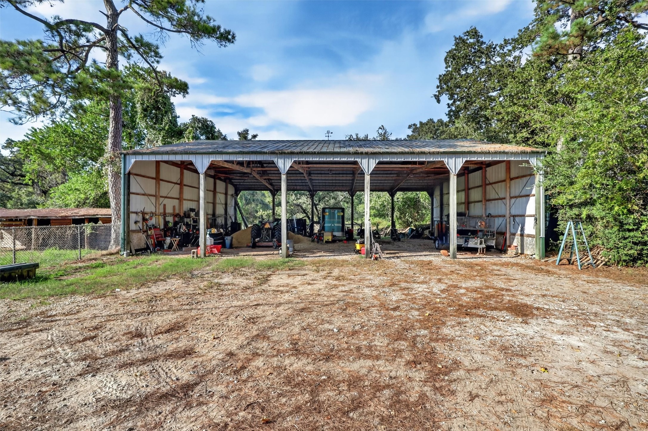 12625 Huffmeister Road Cypress, TX 77429 - Photo 34 of 50 Room for all the tools, equipment, and toys that make ranch life special! This spacious, open-sided covered barn provides generous shelter and storage for tractors, trailers, equipment, and more. Whether maintaining the ranch or pursuing your favorite outdoor hobbies, this versatile structure offers endless possibilities. Equipment and other items currently stored in the barn may be available to convey with the property, subject to negotiation and an acceptable offer.