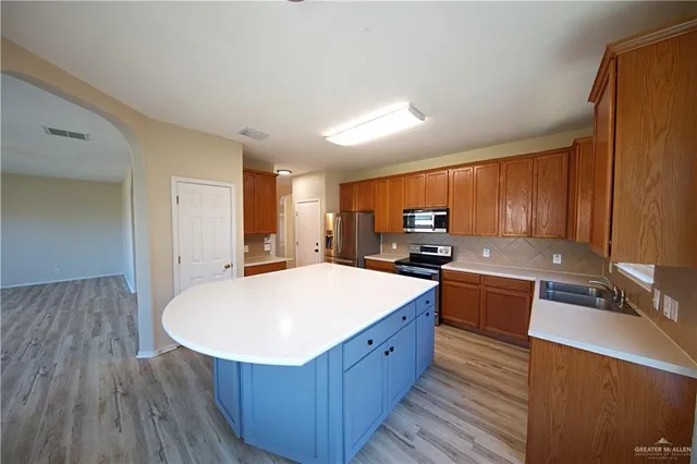 a large kitchen with stainless steel appliances a large counter top a sink a refrigerator and a stove