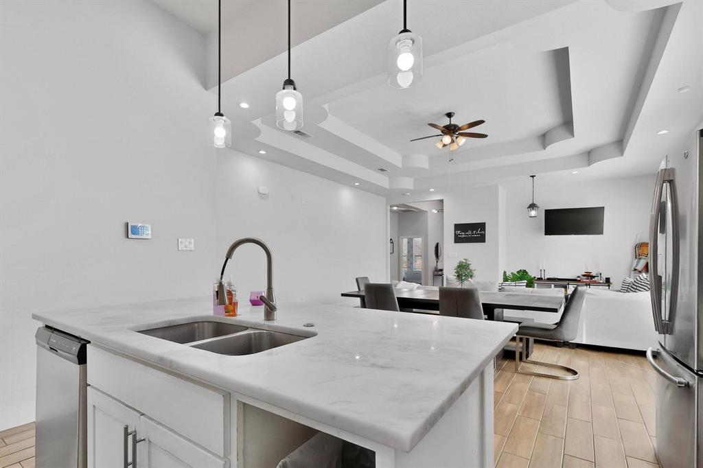 2015 Volga Avenue Dallas, TX 75216 - Photo 11 of 38 Kitchen with decorative light fixtures, white cabinets, stainless steel appliances, wood tiled floors, and a tray ceiling