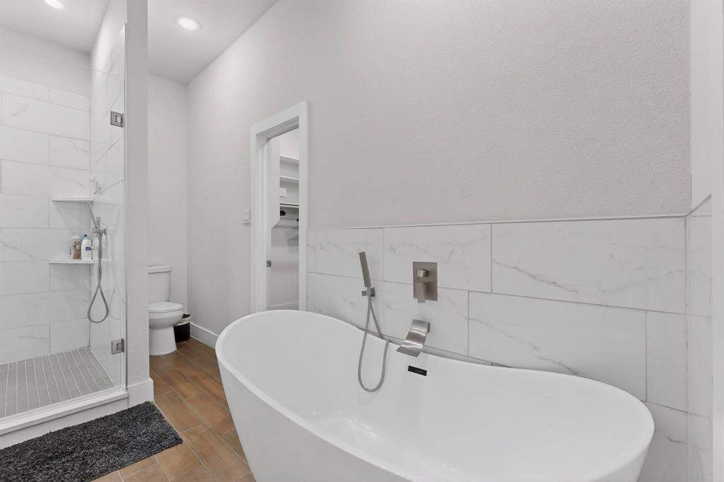 2015 Volga Avenue Dallas, TX 75216 - Photo 18 of 38 Full bath featuring a shower stall, a freestanding tub, tile walls, and wood tiled floors