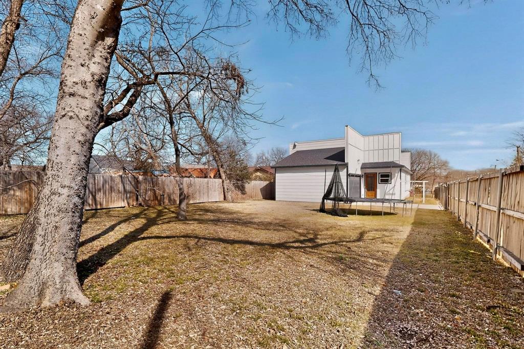 2015 Volga Avenue Dallas, TX 75216 - Photo 36 of 38 Back of house with a trampoline, a fenced backyard, and an outbuilding