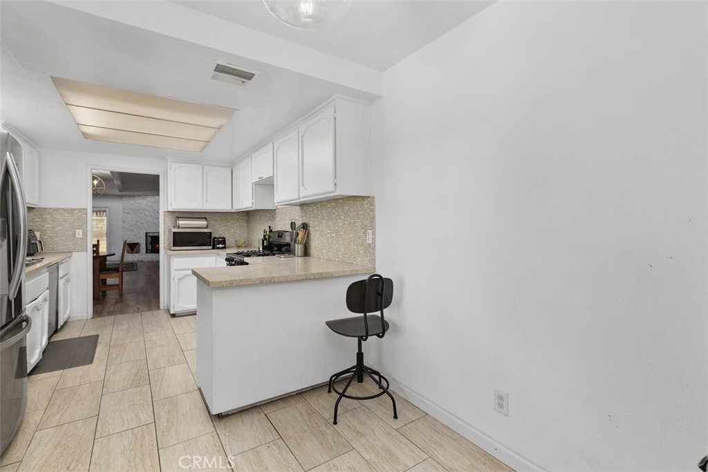 5082 Los Olivos Way Riverside, CA 92505 - Photo 14 of 36 a kitchen with stainless steel appliances kitchen island granite countertop a refrigerator a stove a oven and white cabinets