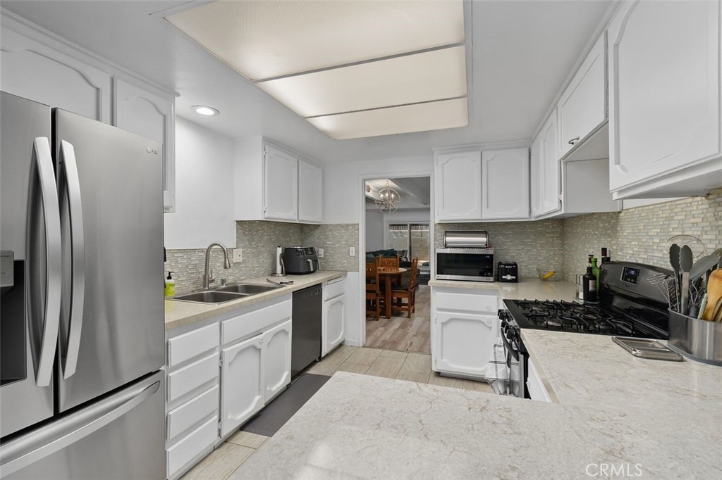 5082 Los Olivos Way Riverside, CA 92505 - Photo 17 of 36 a kitchen with stainless steel appliances granite countertop a refrigerator stove a sink and white cabinets