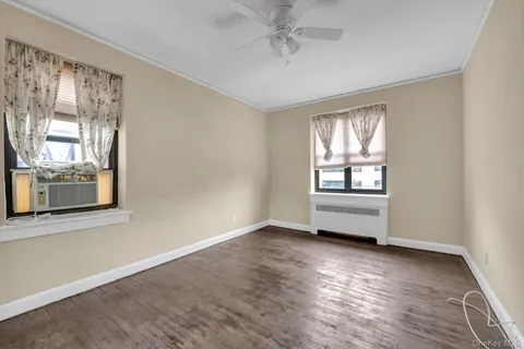 a view of an empty room with a window and wooden floor