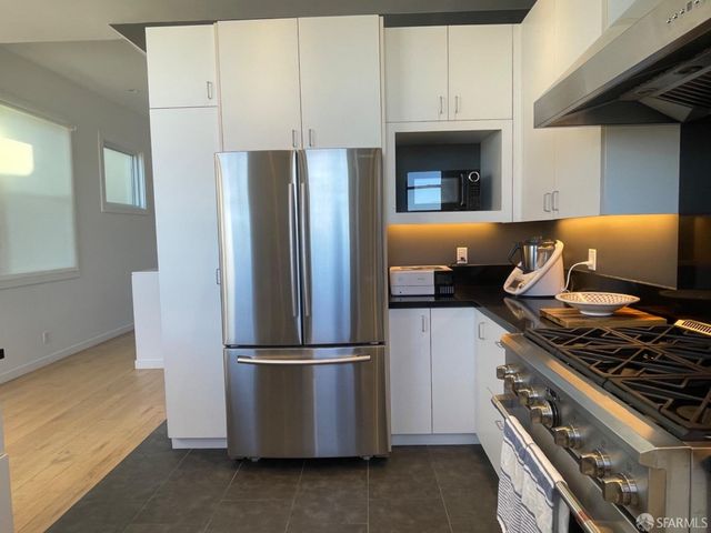 a kitchen with stainless steel appliances a refrigerator a stove and white cabinets
