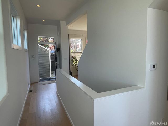 a view of a hallway with wooden floor and staircase