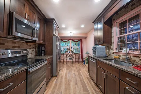 a kitchen with stainless steel appliances granite countertop a stove a sink and a microwave