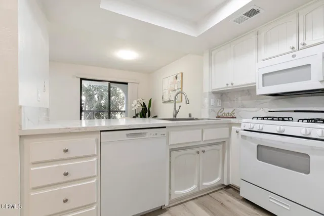 a kitchen with white cabinets and white appliances