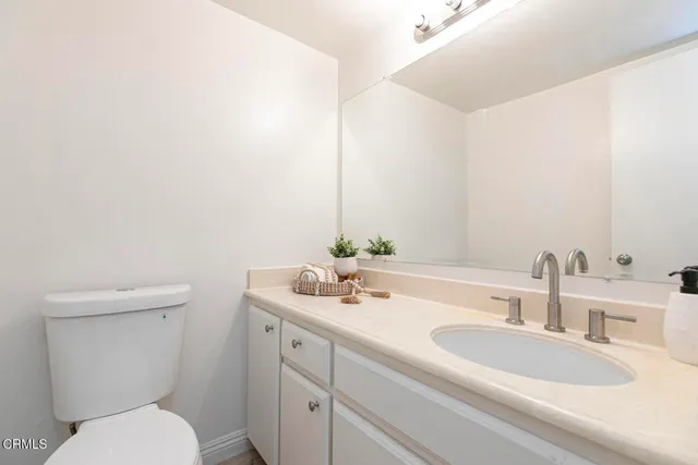 a bathroom with a granite countertop toilet sink and mirror