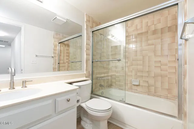 a bathroom with a shower sink vanity mirror and toilet