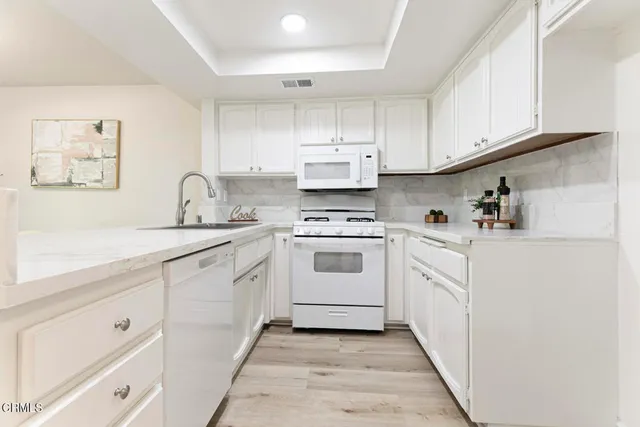 a kitchen with white cabinets a sink and white appliances