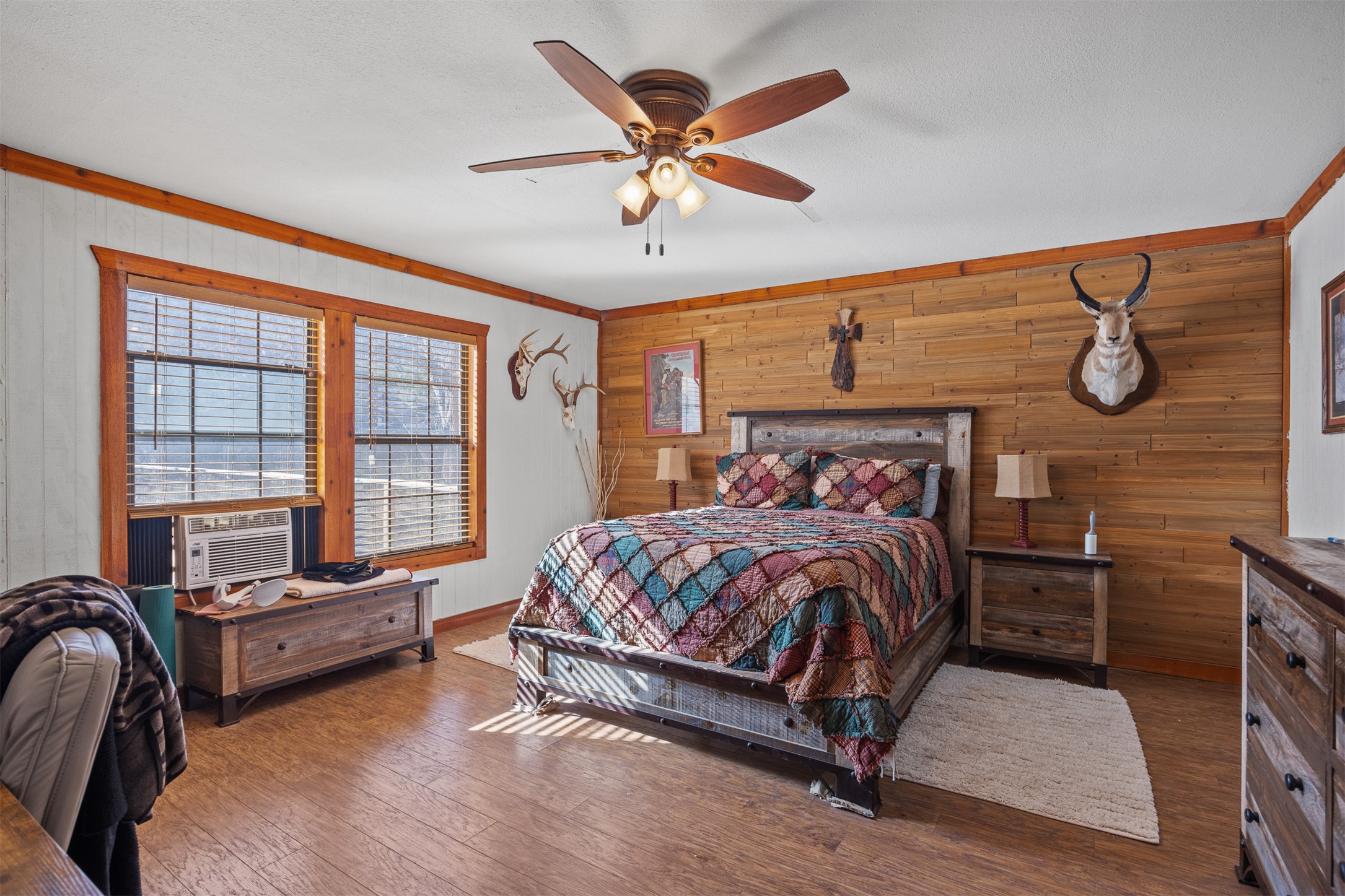 641 Patterson Creek Road Leakey, TX 78873 - Photo 17 of 31 Bedroom featuring wooden walls, dark wood-type flooring, ceiling fan, ornamental molding, and cooling unit