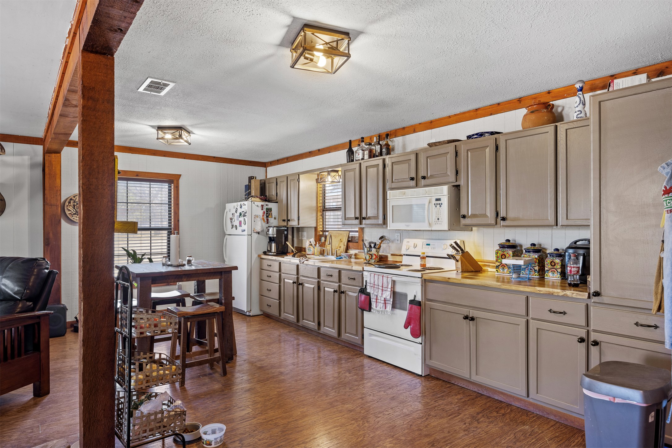 641 Patterson Creek Road Leakey, TX 78873 - Photo 19 of 31 Kitchen featuring light countertops, white appliances, dark wood-style floors, a textured ceiling, and crown molding