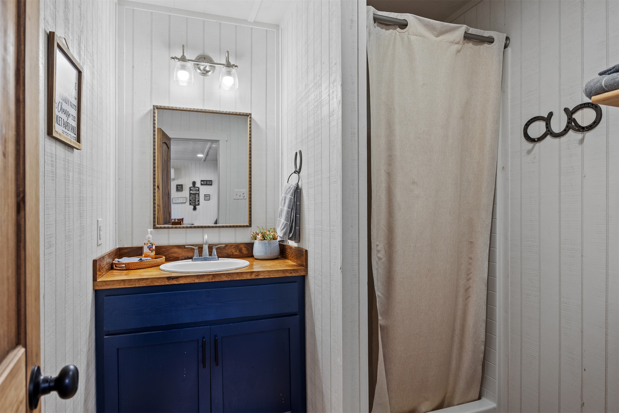 641 Patterson Creek Road Leakey, TX 78873 - Photo 25 of 31 Bathroom featuring vanity, a shower with curtain, and wood walls