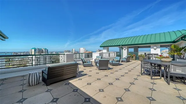 a view of a roof deck with table and chairs a barbeque with wooden floor and fence