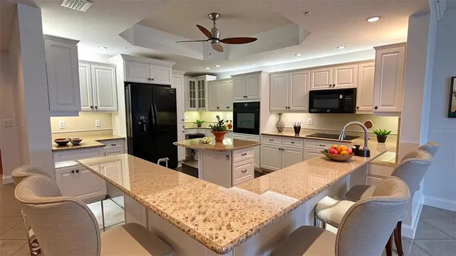 a kitchen with stainless steel appliances kitchen island granite countertop a refrigerator oven a sink a stove a dining table and chairs with wooden floor