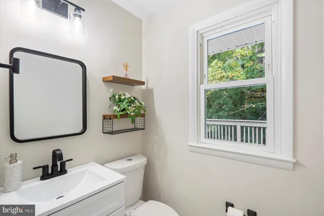 a bathroom with a toilet a sink a mirror and a window