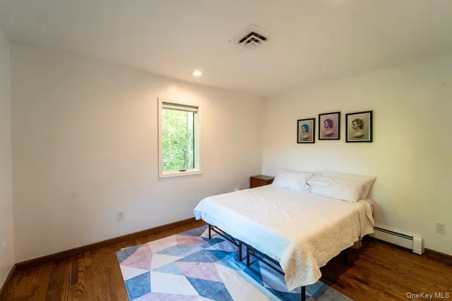 a spacious bedroom with a bed and wooden floor