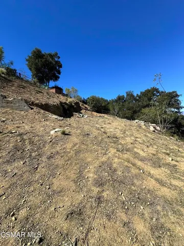 a view of a dry yard with wooden fence and a mountain view