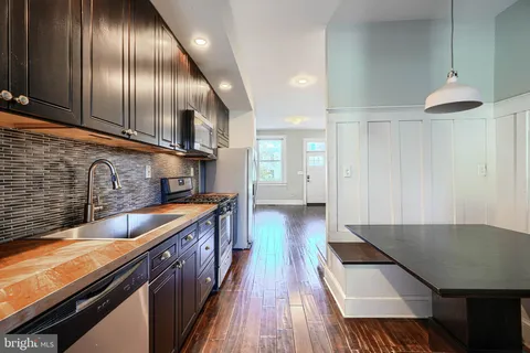 a kitchen with stainless steel appliances granite countertop a sink a stove and a wooden floors