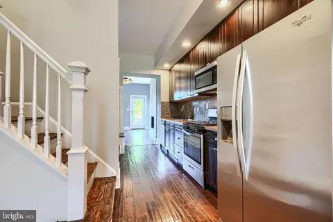 a kitchen with stainless steel appliances granite countertop a refrigerator a stove and a wooden floors