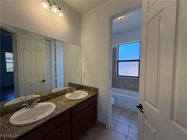 a bathroom with a granite countertop sink a mirror and a bathtub