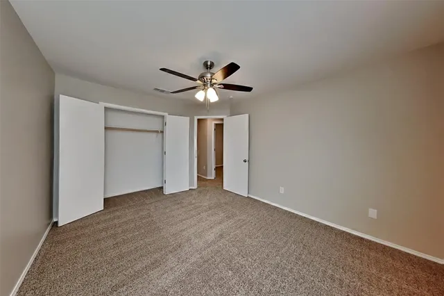 an empty room with closet and a ceiling fan