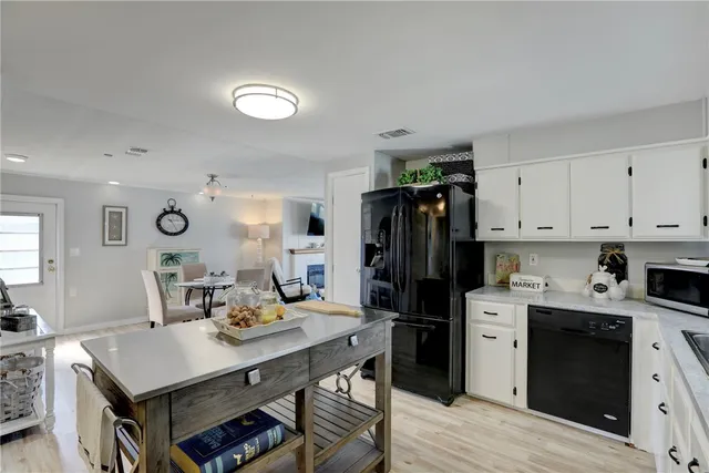 a kitchen with a refrigerator a stove top oven a sink dishwasher and dining table with wooden floor