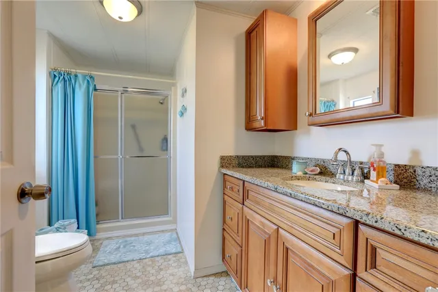 a bathroom with a granite countertop sink a toilet and a shower