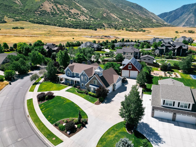 672 Perry Hollow Drive Mapleton, UT 84664 - Photo 12 of 106 Expansive residential property featuring a blue-sided main residence with a covered porch, an attached two-car garage, and a separate red outbuilding with an additional garage