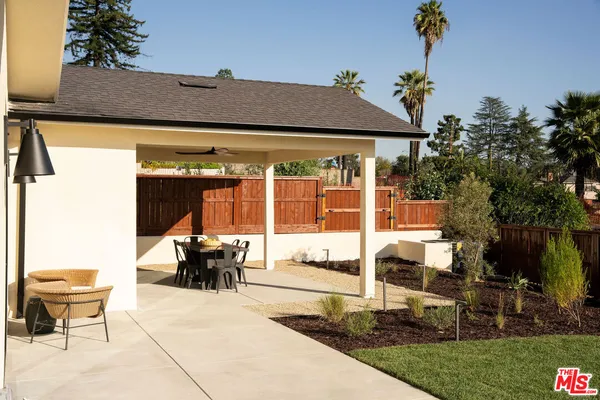 a roof deck with table and chairs potted plants and a large tree