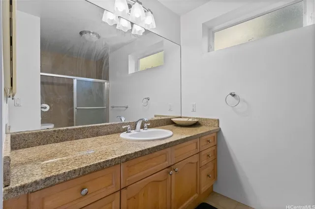 a bathroom with a granite countertop double vanity sink and mirror