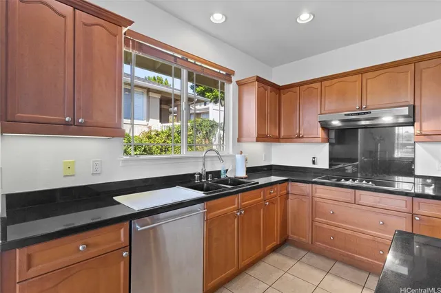 a kitchen with granite countertop stainless steel appliances a sink window and cabinets