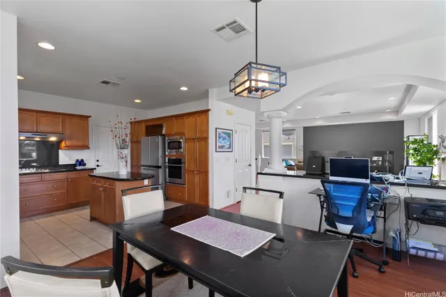 a kitchen with stainless steel appliances kitchen island granite countertop a dining table chairs refrigerator and sink