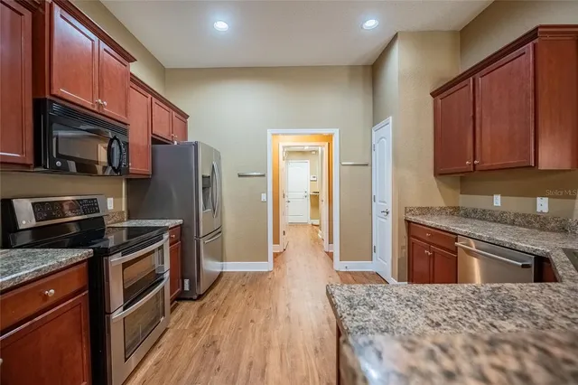 a kitchen with stainless steel appliances granite countertop a refrigerator stove top oven and sink