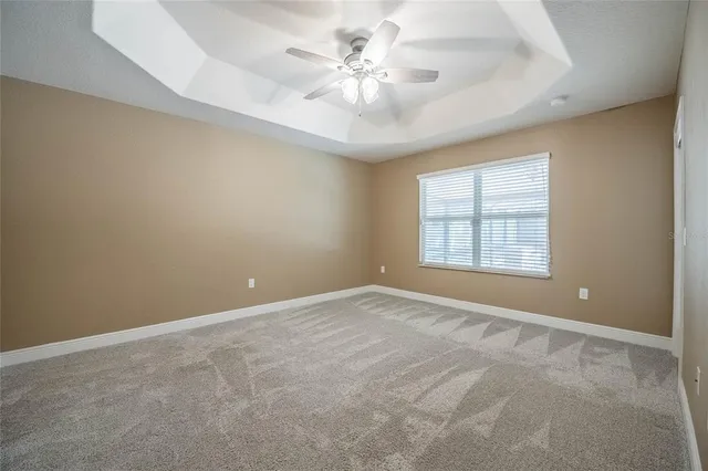 an empty room with windows and ceiling fan
