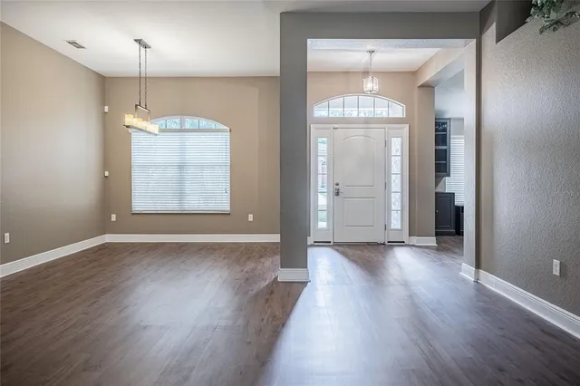 an empty room with wooden floor cabinet and windows