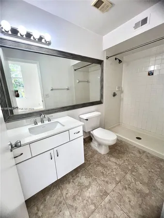 a bathroom with a granite countertop toilet sink and mirror