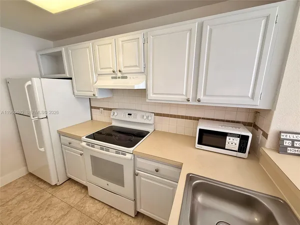 a kitchen with white cabinets and white appliances