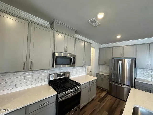 a kitchen with a refrigerator a microwave a sink and cabinets