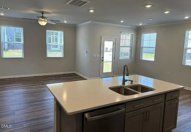 a kitchen with a sink chandelier and wooden floor