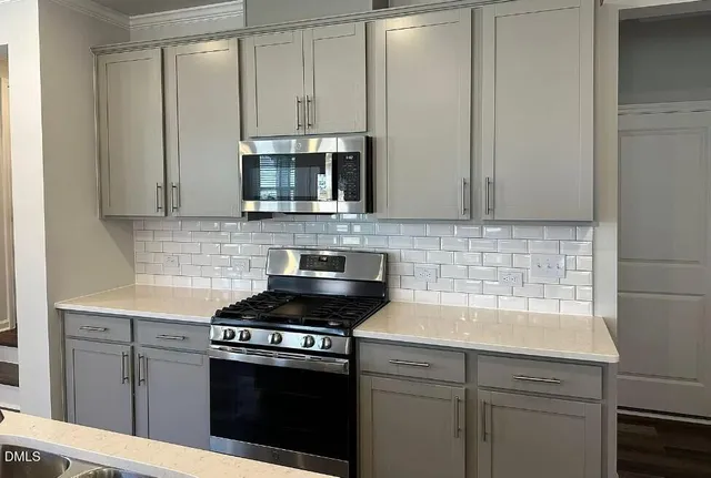 a kitchen with stainless steel appliances granite countertop white cabinets and a stove